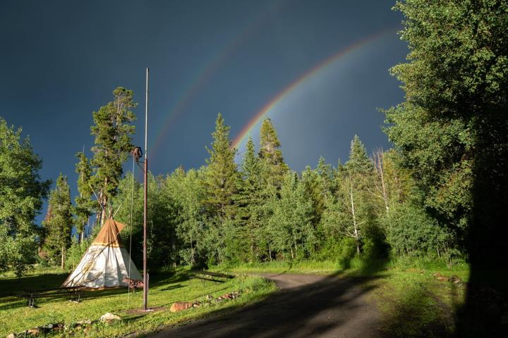 Teepee under grey stormy sky and rainbow
